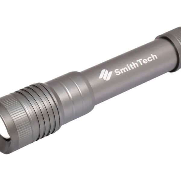 A metallic flashlight with a ribbed grip is positioned diagonally against a white background. SmithTech is printed on the side in white lettering.
