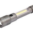 A silver, cylindrical flashlight with a textured grip and a side button. It features a main light at the front and an additional strip light along the side of the barrel. The design is modern and utilitarian.