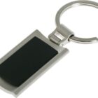 A silver keychain with a rectangular, black center piece. The metal loop at the top is open, designed to hold keys. The design is simple and modern.