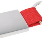 A silver keychain with a rectangular metal plate attached to a red fabric loop and a circular metal key ring. The design is simple and modern, with the red fabric adding a contrast to the metallic elements.
