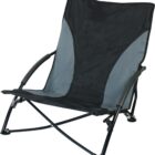 A foldable, low-profile camping chair with a black frame and dark gray and black fabric seat. It has armrests and is designed for outdoor use. The chair has a sturdy build and is angled for comfort.