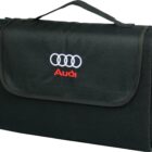 A black folded blanket with a carrying handle. The flap features the Audi logo and the word Audi in red embroidery.