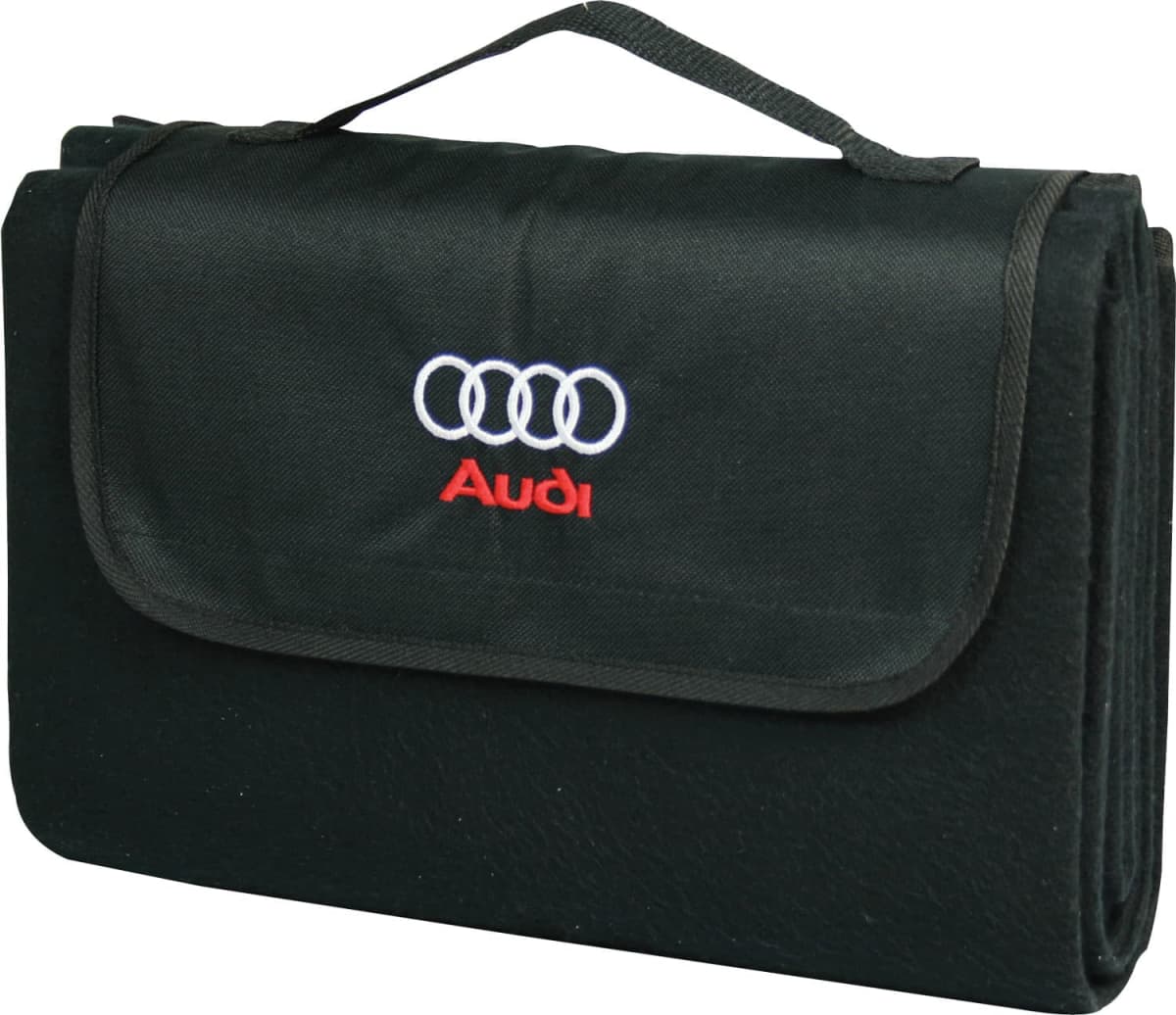 A black folded blanket with a carrying handle. The flap features the Audi logo and the word Audi in red embroidery.
