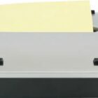 A compact grey and black toaster with a slice of bread partially inserted, ready for toasting. The toaster has a modern design and a slot for one slice.