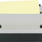 A silver and black desktop dispenser with a yellow sticky note protruding from the top. The dispenser has a sleek design with four black rubber feet for stability.