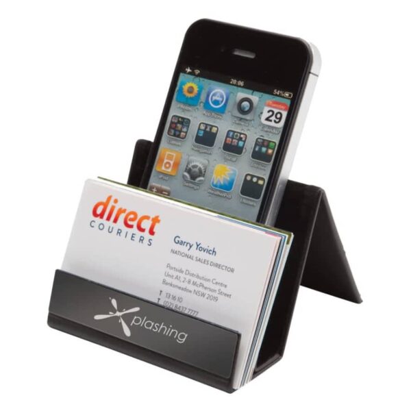 A business card holder displaying business cards in front and an iPhone behind them. The holder is a sleek, black plastic design with a logo at the bottom. The phone screen shows several app icons.