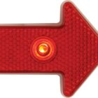 A red arrow-shaped light with a textured surface and a circular central light, pointing to the right.