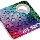 Colorful square bottle opener with a glossy, bubble-patterned surface. The words Labs Inc are partially visible along the side. The opener has a circular cutout at the top for opening bottles.
