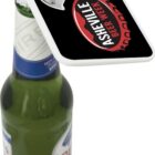 A bottle opener featuring the Asheville Beer Week logo rests atop a capped beer bottle. The opener is square with a bottle cap included in the design.