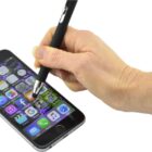 A hand using a stylus to interact with a smartphone screen, displaying various app icons.