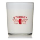 A white candle in a glass holder, featuring a red logo design that includes a winged tire. The logo text reads STUCKEY CLASSIC TYRES.