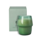 A green candle in a smooth, round holder next to a matching green box with floral accents.