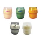 Five colorful candles in two-part glass containers with logos: top row has a pale pink candle with brac; a green with Samsung; and an orange with Netflix. Bottom row shows a gray with Mainvue and a white with a circle design and 21.