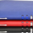 Three stacked leather-bound notebooks in blue, red, and black, each with shiny silver accents along the spine. The notebooks are neatly aligned, creating a colorful and organized appearance.