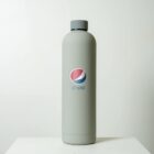 A gray reusable bottle with a modern design featuring the Pepsi logo on its front is placed on a white surface against a plain background.