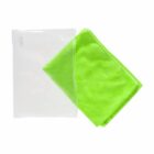 A bright green towel is partially folded next to a transparent plastic bag on a white background. The towel has a soft texture and is placed to the right of the bag.
