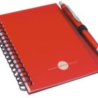 A red spiral-bound notebook with Global Media Group printed on the cover, accompanied by a red and silver pen clipped to the open edge.