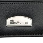 Close-up of a metallic logo plaque with the word Avline and an abstract design, set against a textured black leather background.