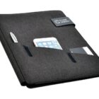 A black portfolio organizer with a pen, smartphone, and business cards in its exterior pockets. The front flap has a magnetic closure with a logo.