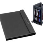 A black leather portfolio cover is on the left, displaying the engraved text CREDIT SUISSE. To the right, a small black organizer holds four pens, a USB cable, and a pair of white earbuds.
