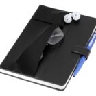 A closed black notebook with a pair of glasses tucked under its elastic strap, white earbuds on top, and a blue pen secured by a pen loop on the side, isolated on a white background.