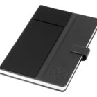 A black notebook with a textured cover, featuring a debossed circle design in the lower right corner. It has a magnetic closure strap and a pocket on the front. The notebook is set against a white background.