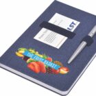 A dark blue notebook with a pen attached to the cover and business cards partially tucked inside. The cover also features colorful fruit graphics and the words The Fruit Basket.