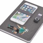 A gray notebook with a smartphone and USB drive strapped to its cover. The notebook features an illustration of a soccer player kicking a ball and the word ACTIFIT.