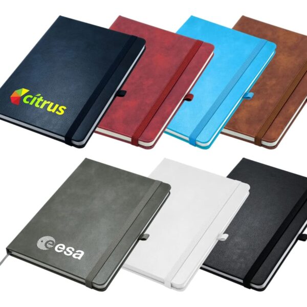 A collection of seven notebooks in various colors: dark blue, red, light blue, brown, gray, white, and black. Two feature logos: Citrus on the dark blue and Esa on the gray. They are arranged in a staggered layout.