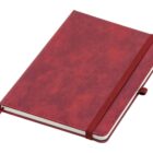 A closed, red hardcover notebook with an elastic band around it and a ribbon bookmark. The surface has a textured appearance.