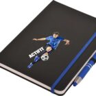 A black notebook featuring an illustration of a soccer player in a blue uniform, kicking a soccer ball. The word ACTIFIT is printed beside the player. A blue pen is attached to the notebooks side with an elastic band.