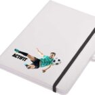 A white notebook with a black elastic band. A cover design shows a soccer player in mid-air kicking a ball, with the word ACTIFIT below the image.