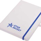 A white notebook with rounded corners and a blue elastic band. The cover features a blue star logo and the words STAR INVEST. A white ribbon bookmark is visible.