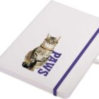 A closed notebook with a white cover featuring a photo of a tabby cat. The word PAWS in purple letters is printed below the cat. A purple elastic band is wrapped around the notebook, and a white ribbon bookmark is visible.