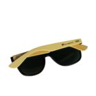 Sunglasses with black lenses and light brown bamboo arms, featuring the Champion logo on the side. They are folded and placed against a white background.