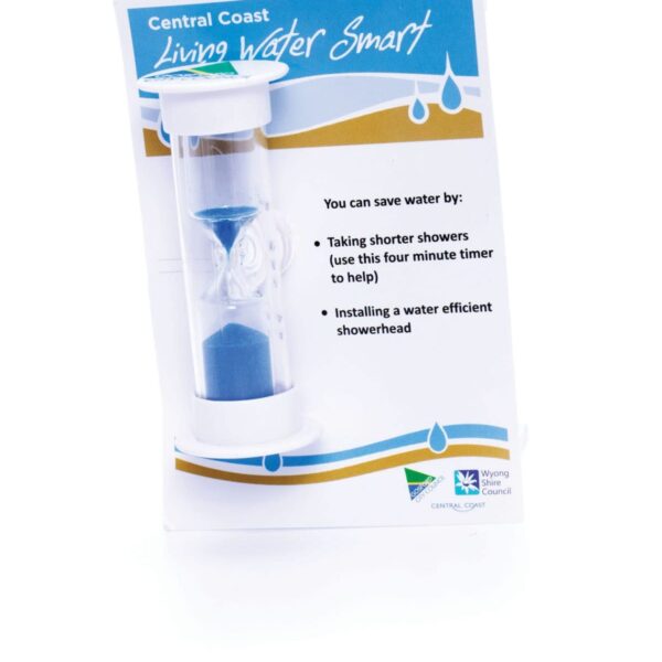 A white four-minute sand timer with blue sand is positioned next to a card. The card promotes water saving, suggesting shorter showers and installing efficient showerheads, with the title Central Coast Living Water Smart and logos at the bottom.