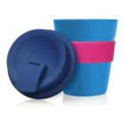 Two blue reusable cups with lids and a pink band around the middle of one cup. The lids have a small flap for sealing. The cups are positioned side by side, with one lid placed on top.