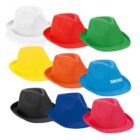 A collection of colorful fedora hats displayed in two rows. Colors include white, red, green, yellow, orange, blue, black, and pink. The blue hat has the word Traveling printed on it. Each hat features a classic pinched crown and wide brim design.
