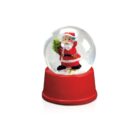 A snow globe featuring Santa Claus holding a green wreath, set on a red base. Santa wears his traditional red suit with black boots and belt. The globe contains white snowflakes.