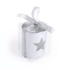 Small white candle in a clear box, adorned with a silver ribbon tied into a bow. The candle features a star-shaped cutout.