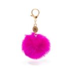A pink fluffy pom-pom keychain with a gold clasp and oval tag engraved with a crown symbol.