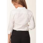A person with long brown hair is facing away from the camera, wearing a white dress shirt and black pants. The shirt has three-quarter sleeves, and the person is slightly turned to the side, revealing a bracelet on their right wrist.