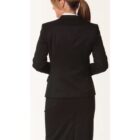 A woman with brown hair tied in a ponytail is seen from the back. She is wearing a black suit jacket and a matching knee-length skirt, paired with a white collared shirt. The background is plain white.