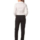 Rear view of a person with long hair tied back, wearing a white button-up shirt and black pants, standing with hands in pockets against a plain white background.