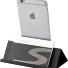 A smartphone is propped up on a black stand with a business card labeled Scientific and additional contact details partially visible.