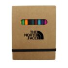 A brown cardboard box displaying The North Face logo in black. The box has a cutout revealing a row of colorful pencils inside. A black elastic band wraps around the bottom part of the box.