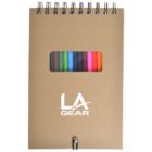 A spiral-bound notebook with a brown cover featuring the LA Gear logo in white. It has a small window displaying colorful markers inside. A pen is clipped at the bottom.