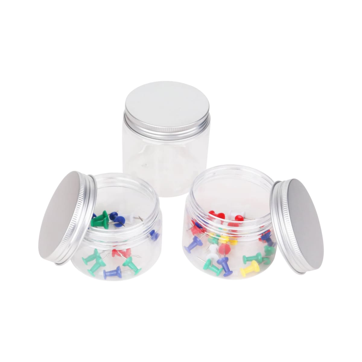 Three clear jars with silver lids on a white background. Two jars have colorful push pins inside, one contains green and blue pins, the other holds red, yellow, and purple pins. The third jar is empty.