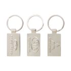 Three silver keychains feature embossed logos: one with Coffey Ford and a Ford logo, another with a Kia logo and Harrison Kia, and the third with Mitsubishi and Carson Mitsubishi. All are rectangular with a ring.