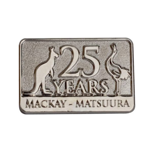 Silver rectangular pin featuring 25 Years in large, raised letters between engravings of a kangaroo and an emu. Below, it reads MACKAY-MATSUURA.